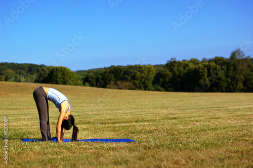 Girl practicing yoga in a summer meadow.