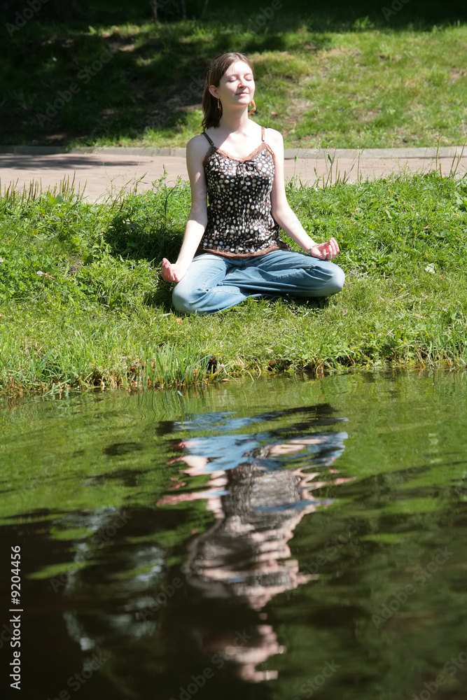 beautiful girl meditating near by water