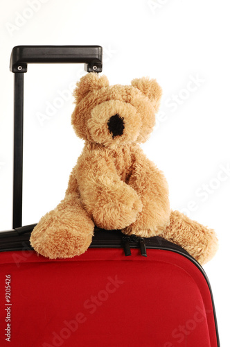 teddy bear toy on a red suitcase with long handle