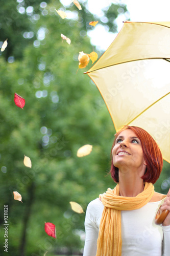 beautiful young girl under yellow umbrella in the autumn park