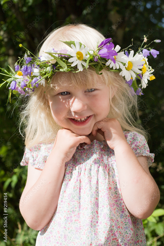 Obraz premium happy little girl in flowers wreath on green meadow