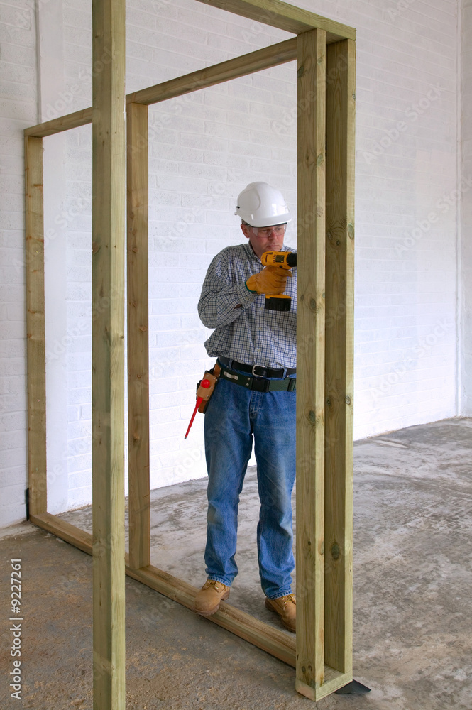 Carpenter drilling into some timber framework in a new home.