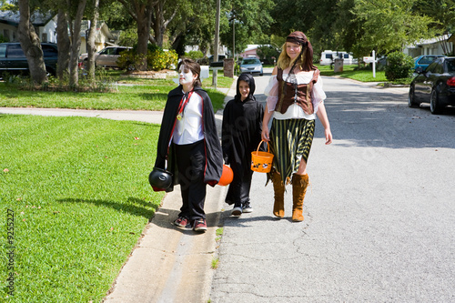 Kids in halloween costumes trick or treating in neighborhood.