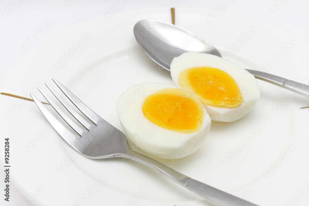 Cooked egg put on white plate with folk and spoon. Cooked egg put on white plate with folk and spoon.