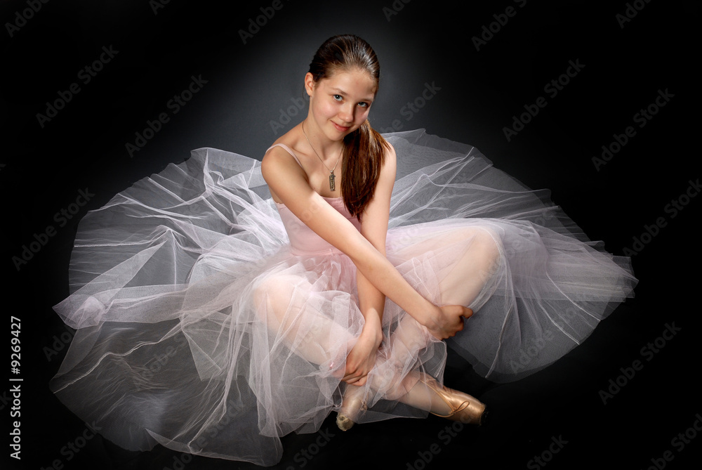 Young ballerina in rose dress sitting on the floor