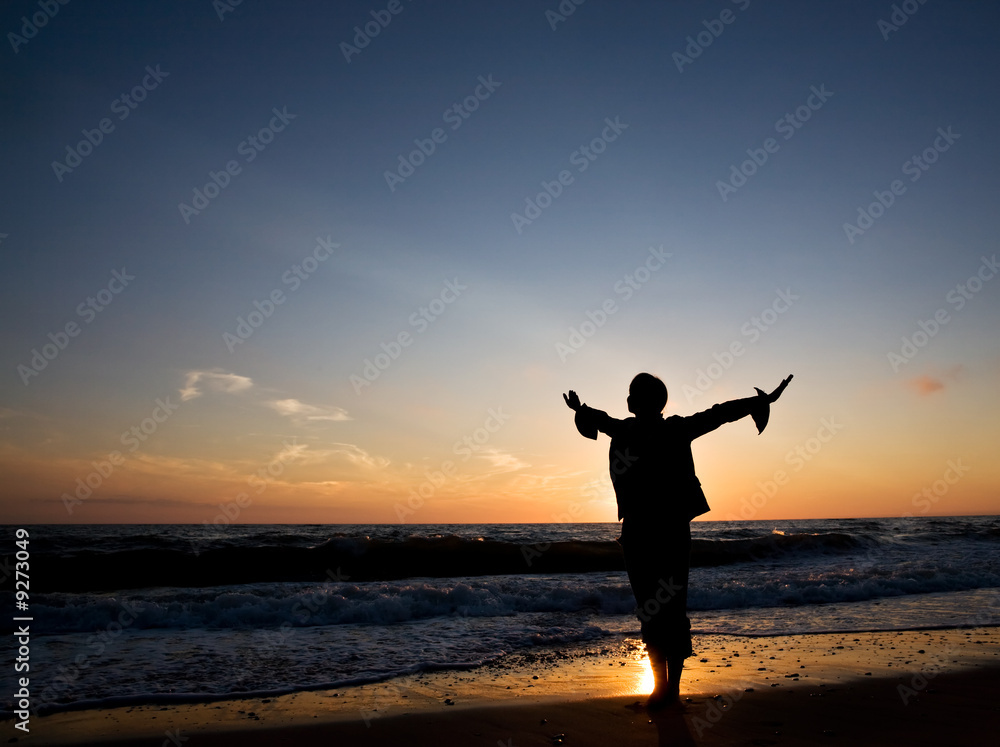 Silhouette of happiness woman at seashore on the sunset..