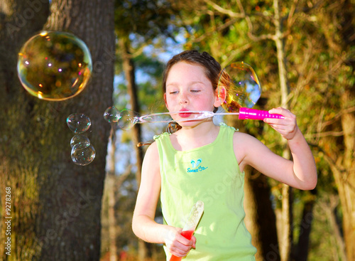 Young girl in woods blowing big bubbles