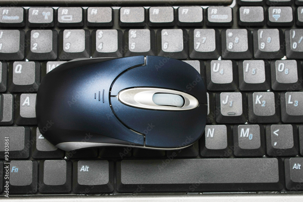 A wireless mouse put on keyboard of a laptop. A wireless mouse put on keyboard of a laptop.