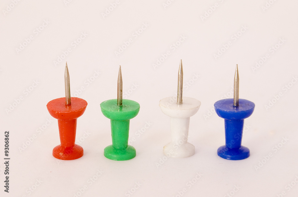 four coloured push-pins standing on a white background