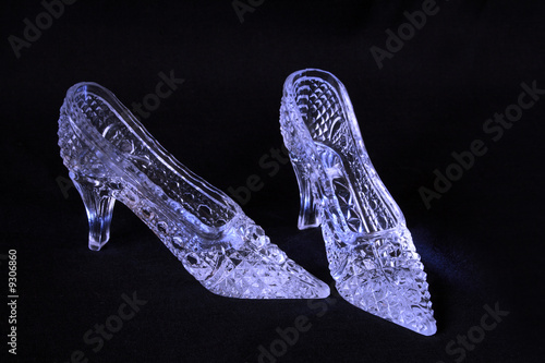Two nice glass slippers lying on dark background