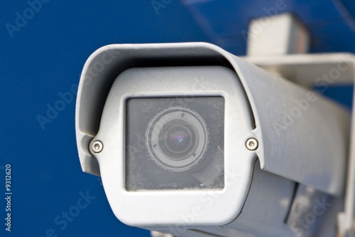 Detail of a white security camera. Isolated on blue background.