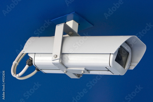 White security camera isolated on blue background.