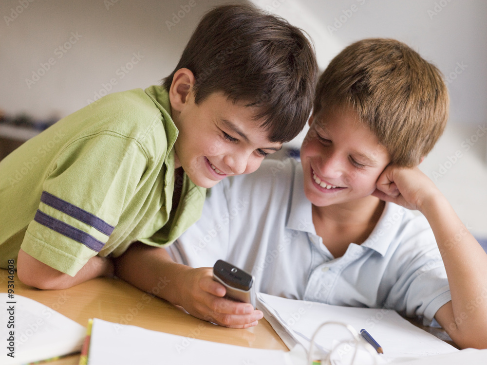 Two Young Boys Distracted From Homework, Playing With Cellphone Two Young Boys Distracted From Homework, Playing With Cellphone