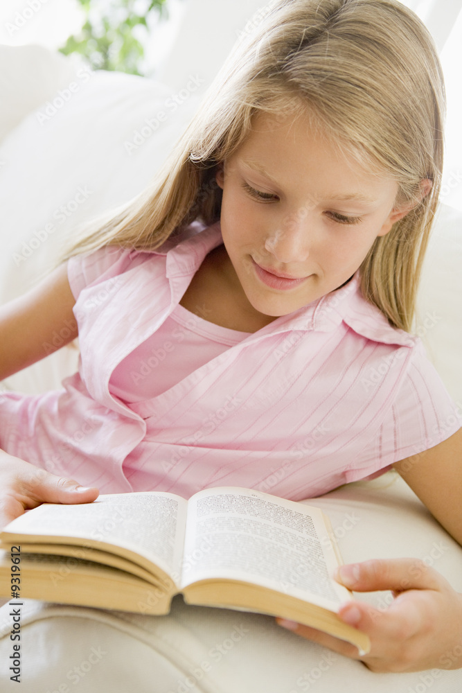Young Girl Sitting On A Sofa Reading A Book Young Girl Sitting On A Sofa Reading A Book