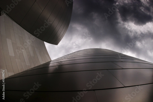 photo of modern curvy metal building with cloudy sky