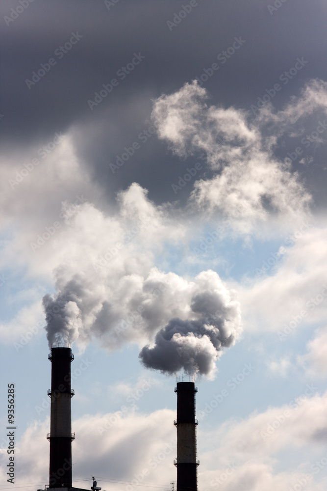 Two chimneys from which there is a smoke against the sky Two chimneys from which there is a smoke against the sky