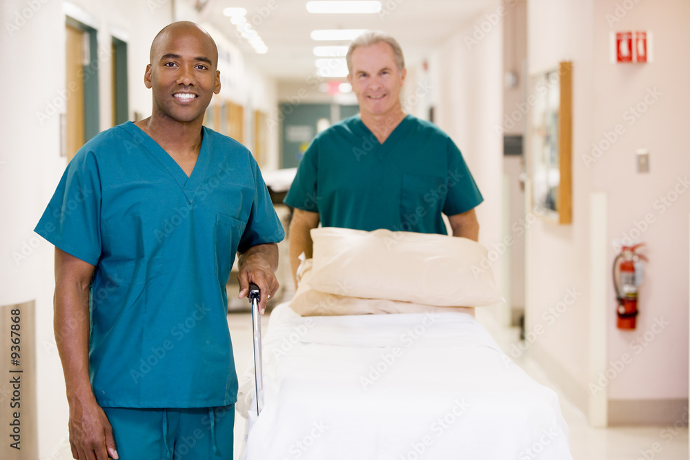 Two Orderlies Pushing An Empty Bed Down A Hospital Corridor Two Orderlies Pushing An Empty Bed Down A Hospital Corridor