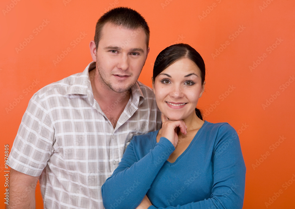 casual couple together standing on orange background casual couple together standing on orange background