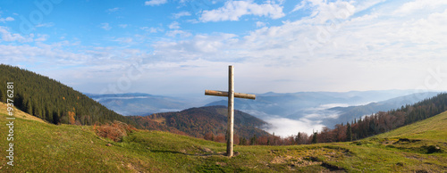 Wood cross on fall mountain plateau.