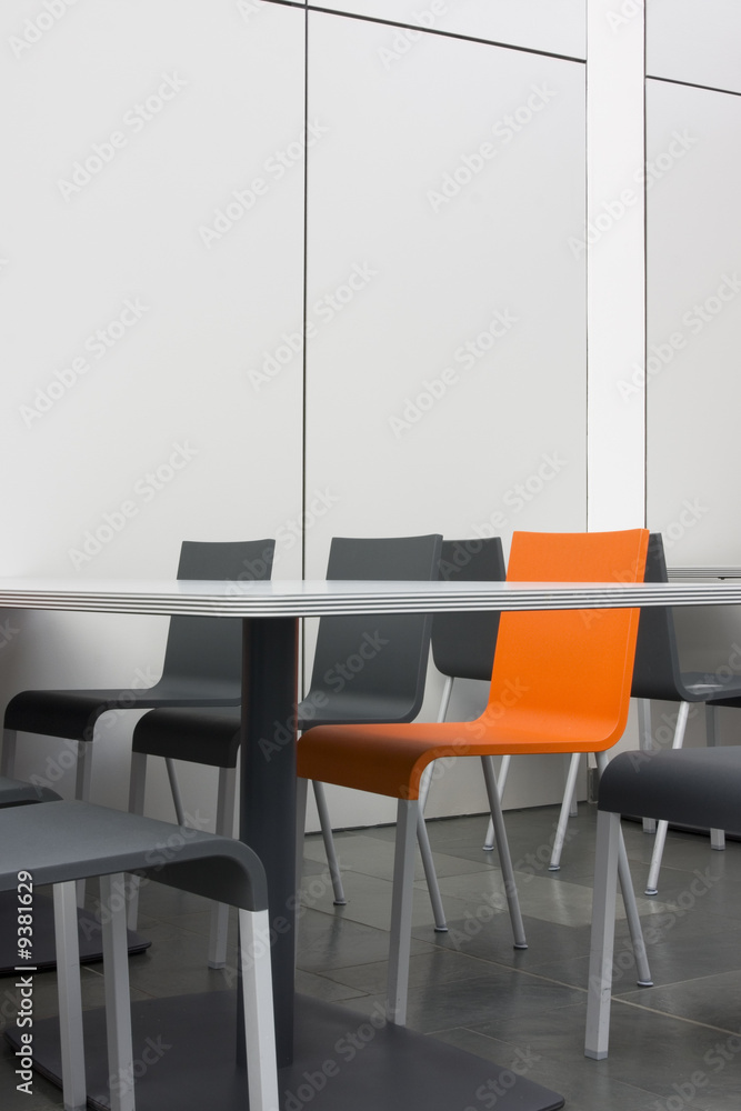 Orangefarbener Stuhl unter grauen Stühlen. Orangefarbener Stuhl unter grauen Stühlen.