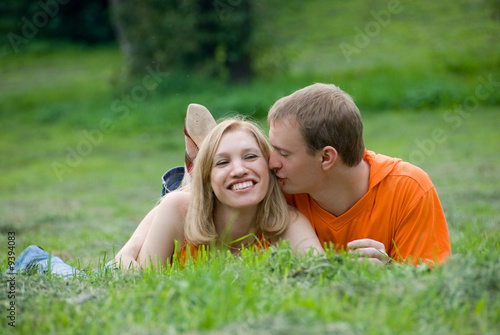 Loving couple lies and embraces on a green grass © Anton Gvozdikov