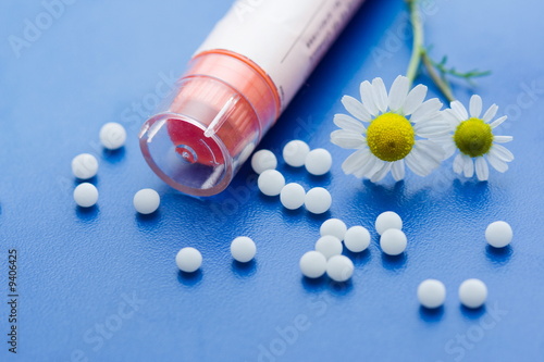 Chamomile flower and homeopathic medication on blue surface photo