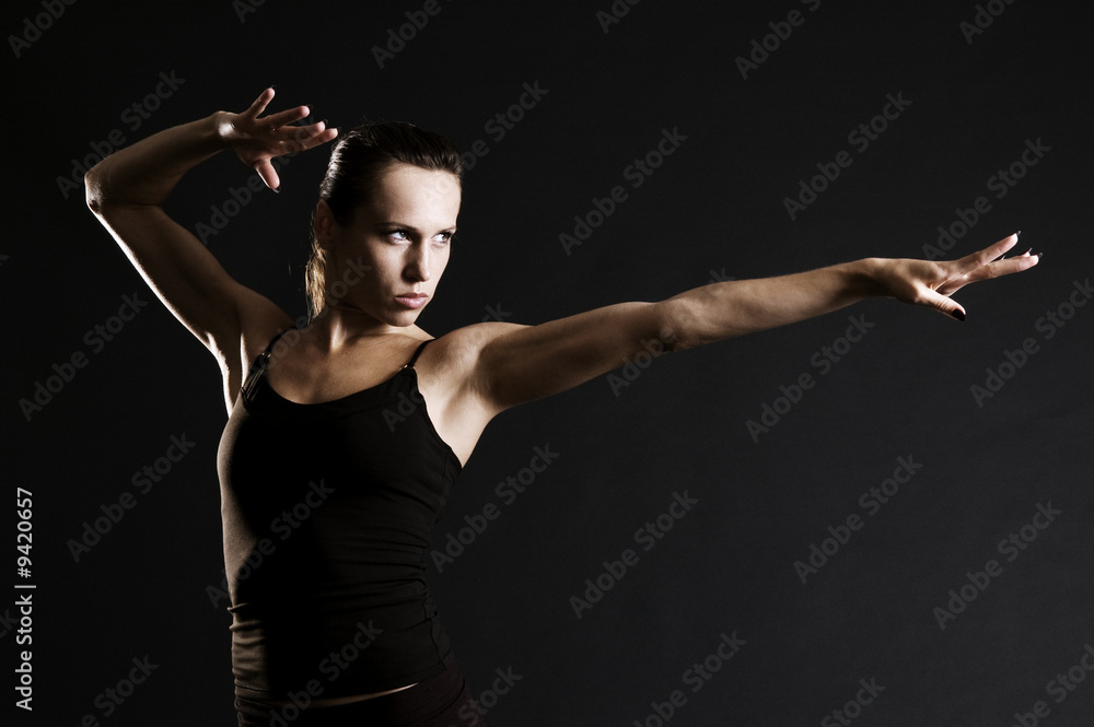 serious sportswoman in pose over dark background