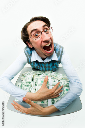 Portrait of greedy male raking in dollars and being glad photo
