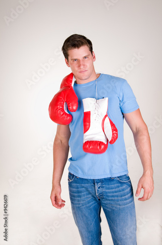 rugged sexy man stands with boxing gloves over shoulders