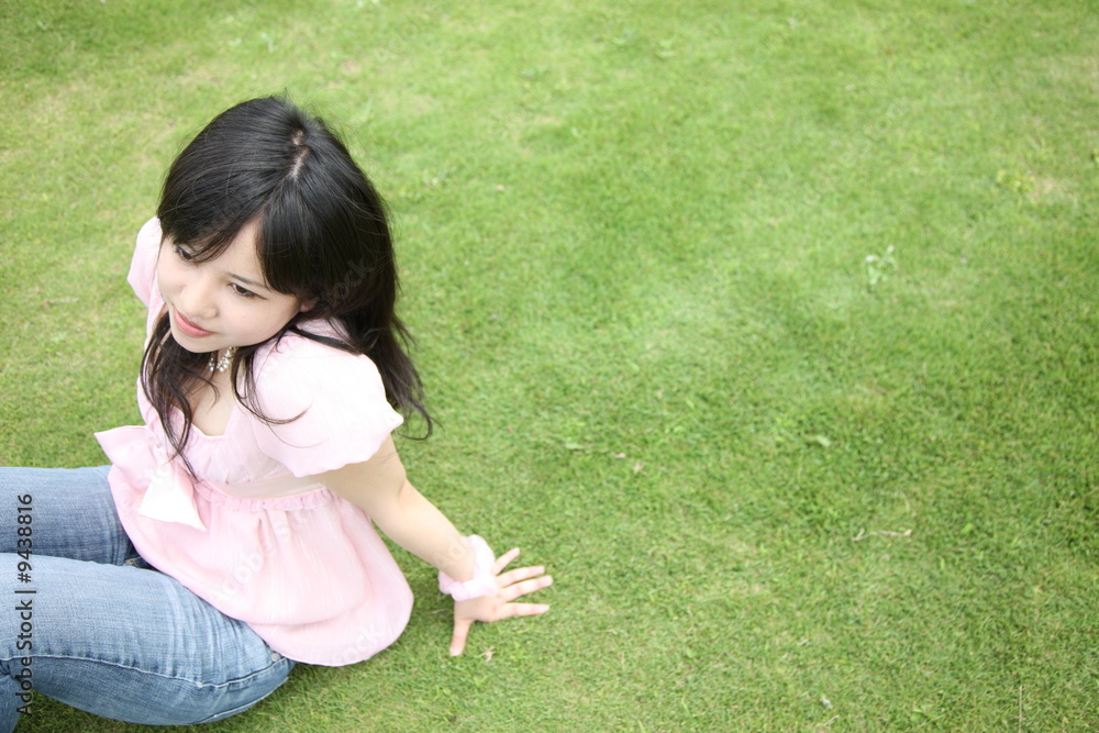 young woman sits down on a lawn