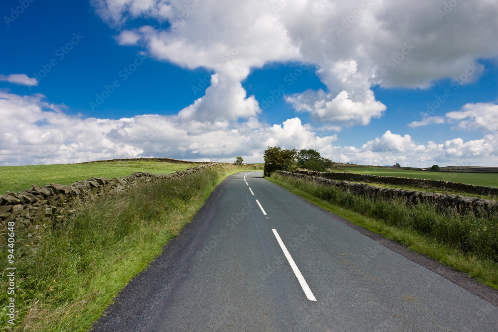 Rural Lane Disappears over a hill, Blue Sky, Cumulus Cloud