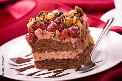 Delicious cream cake with cherry on the red satin.