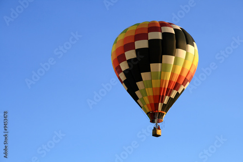 Multicoloured hot air balloon in the blue sky. © Studio Light & Shade