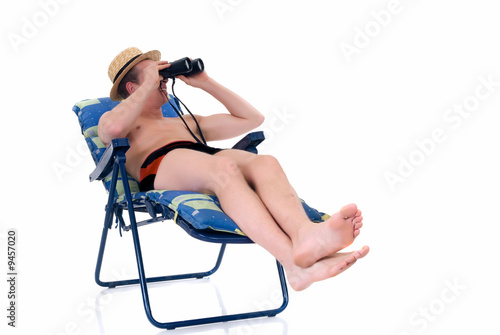 Young man in deck chair looking trough magnifying glass,