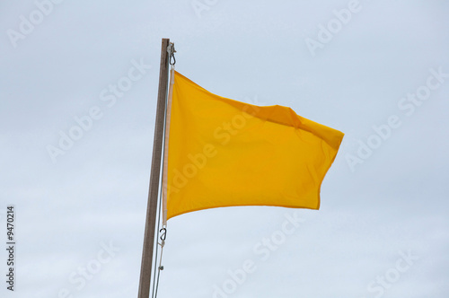 Yellow flag on the beach waving in the wind