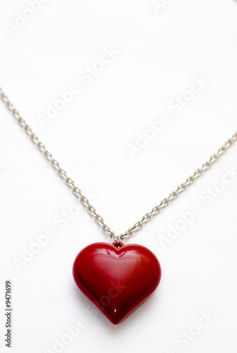 A silver necklace with a large heart shaped pendant