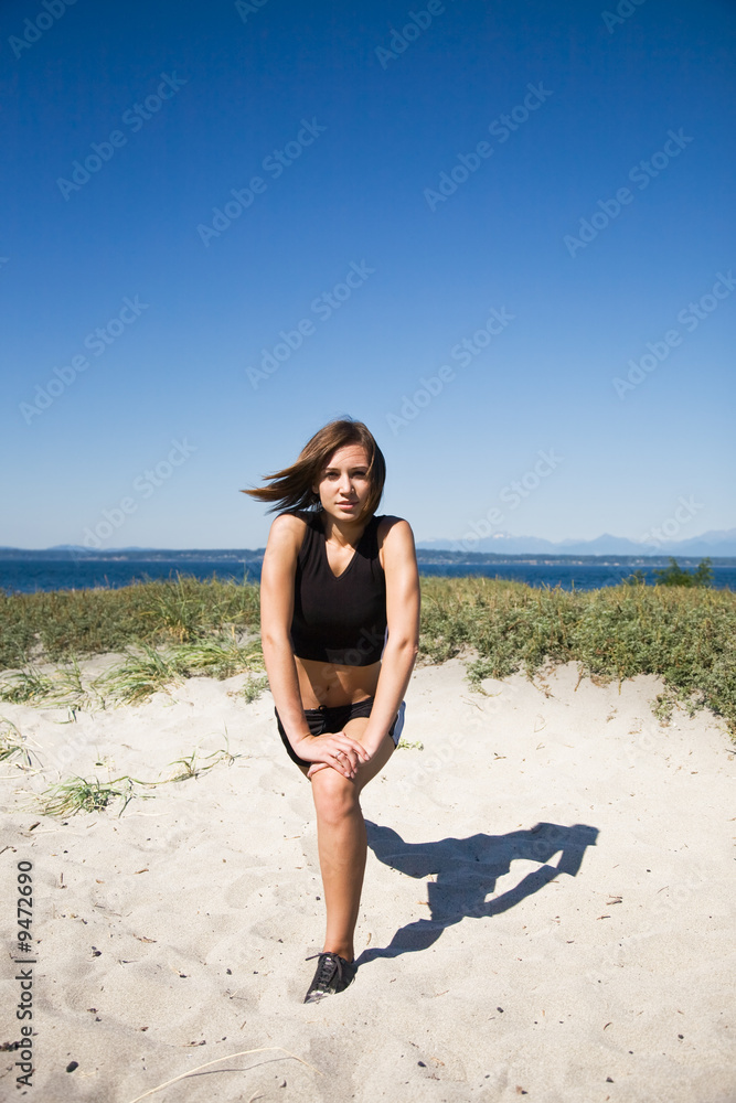 A caucasian girl stretching before exercising on the beach A caucasian girl stretching before exercising on the beach