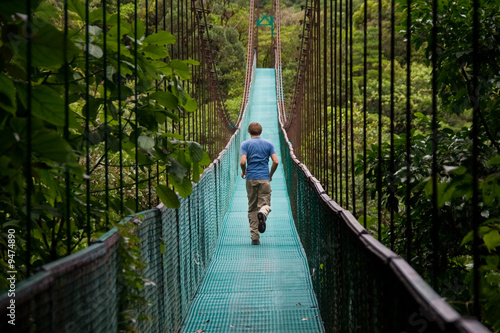young man running over a jungle bridge