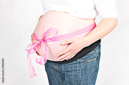 Belly of pregnant woman with pink bow