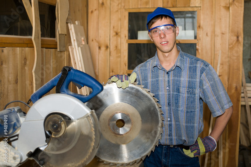 The carpenter holds a circular saw blade in a hand. photo