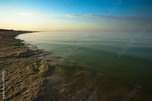 Sunrise on sea with part of sand beach. Black Sea, Russia