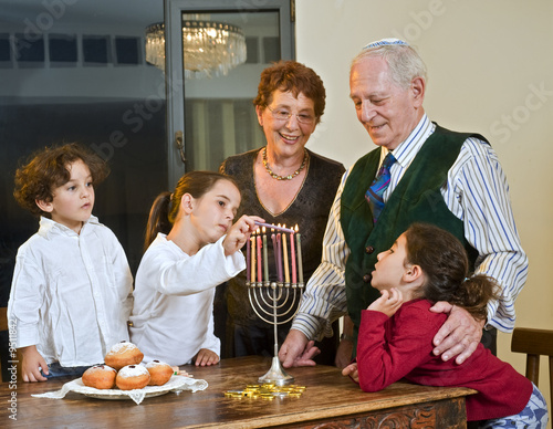 grandperents and grandchildren lightening Hanukkiyah together
