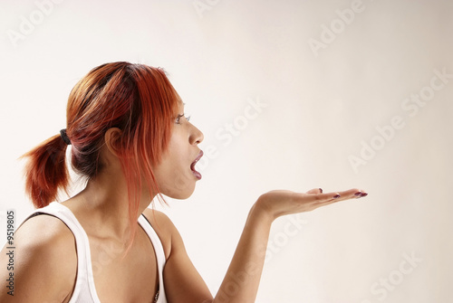 young redheared woman blow on opened hand