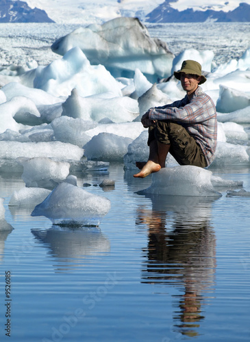Man, sitting on ice in Jokulsarlon lagoon, Iceland