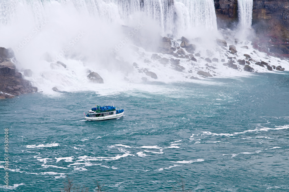 Fototapeta premium A boat sailing in a river next to Niagara falls
