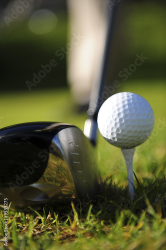 A golfer in action, driver lined up with the ball on a tee.