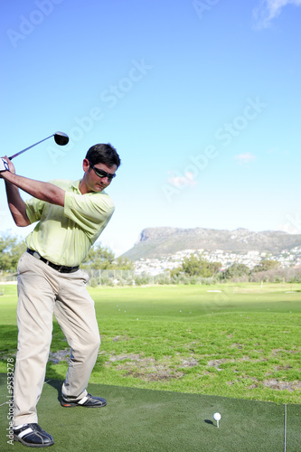 A golfer in action on a practice range, hitting the ball.