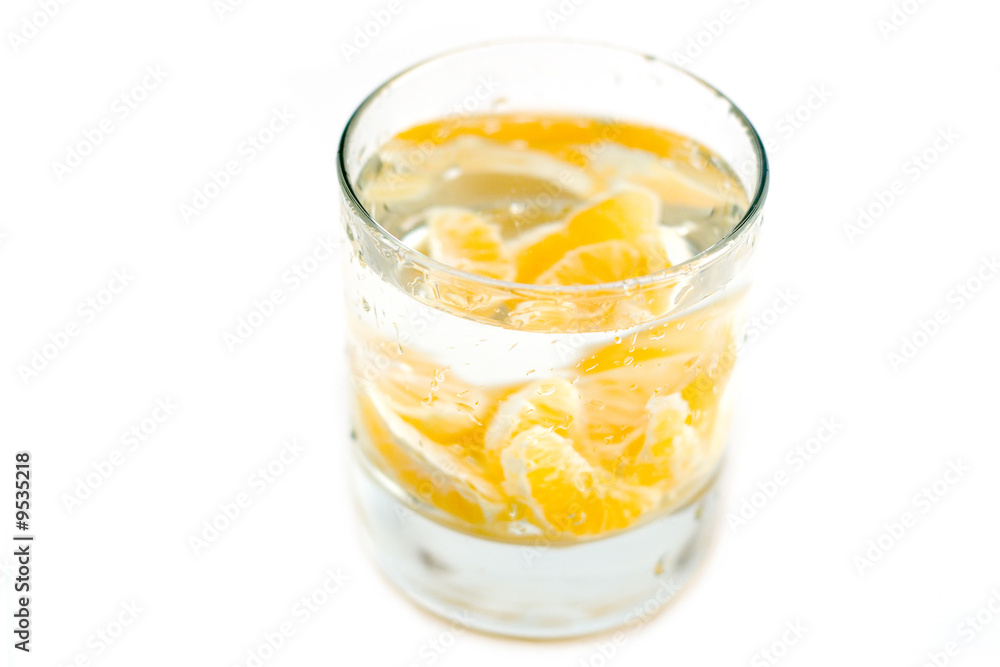 lobules of mandarine at glass water isolated on white