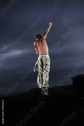 young man dancing and jumping  on top of the building © .shock