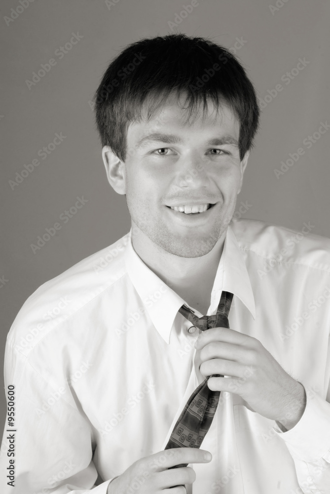 young businessman smiles and corrects for  tie